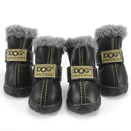 Four black leather dog boots with grey fur lining, adjustable straps, and non-slip soles.
